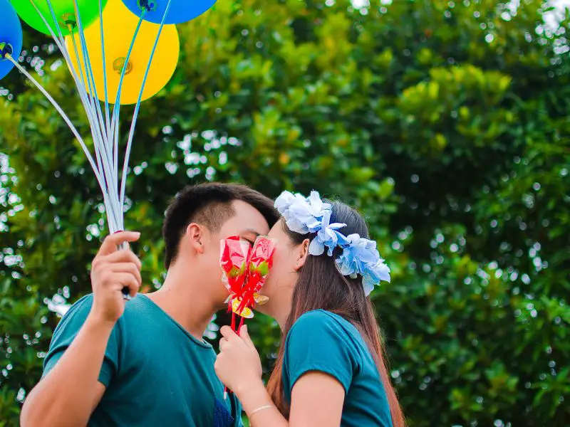 Couple kissing while holding balloons